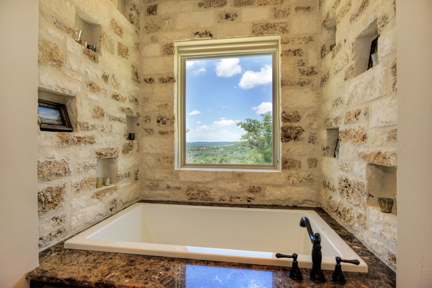 Primary bathroom soaking tub beside a window overlooking the hills